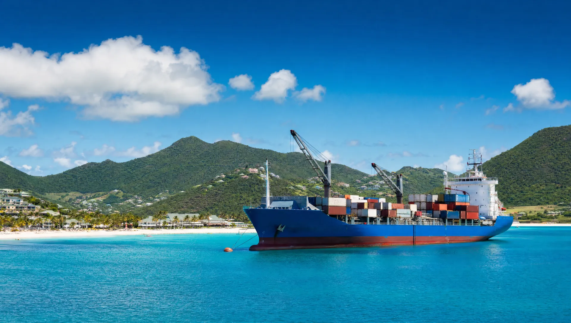 A cargo ship anchored in a mountain-ringed bay at Saint Martin